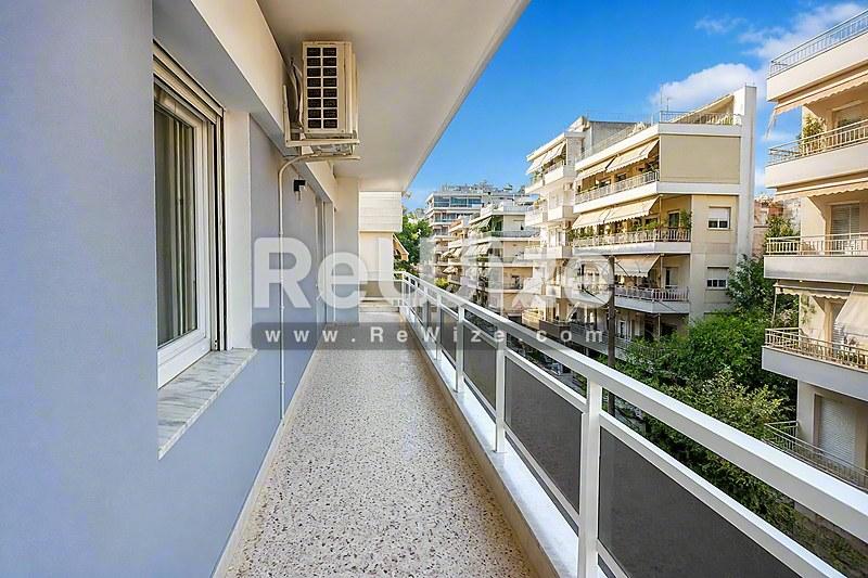 Просторný balkón διαμερίσματος στη Χαλκιδική με σύγχρονες γυάλινες κάγκελα και θέα στα κτίρια.