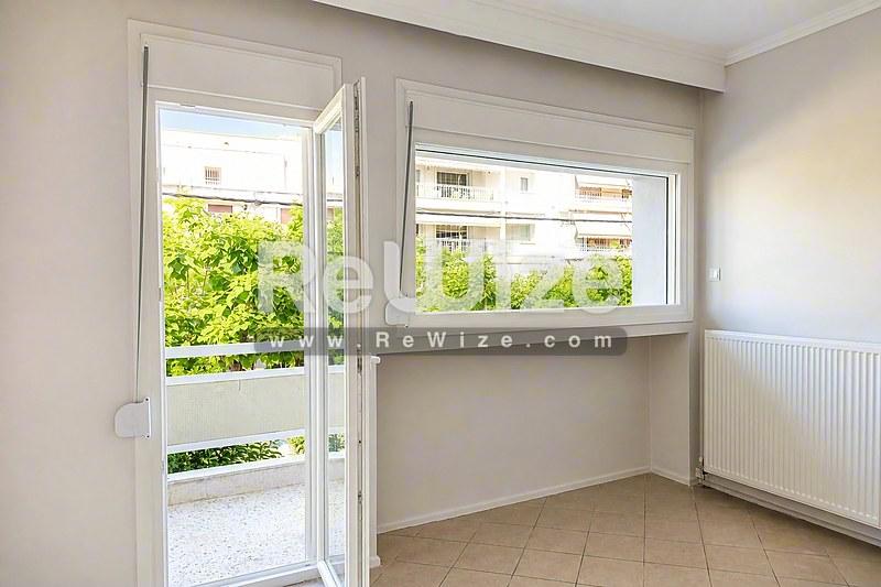 Φωτεινό σαλόνι διαμερίσματος στη Χαλκιδική με γυάλινη πόρτα πρόσβασης σε μπαλκόνι.