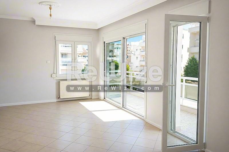 Φωτεινό σαλόνι διαμερίσματος στη Χαλκιδική με μεγάλες γυάλινες πόρτες μπαλκονιού και άφθονο φυσικό φως.