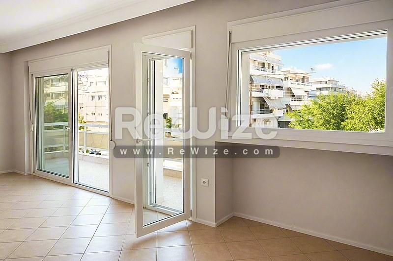 Φωτεινό σαλόνι διαμερίσματος στη Χαλκιδική με γυάλινες πόρτες, μεγάλα παράθυρα και ξύλινο δάπεδο.