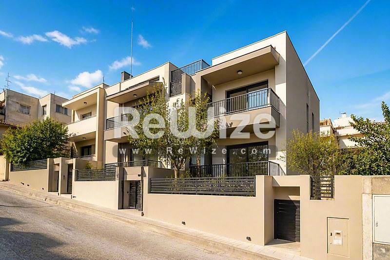 Σύγχρονη πρόσοψη διαμερίσματος με ανοιχτόχρωμη επένδυση πετρόχτιστη και μπαλκόνια στη Χαλκιδική, με σύγχρονη αρχιτεκτονική.