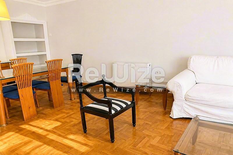 Φωτεινό σαλόνι διαμερίσματος στη Χαλκιδική με ξύλινο δάπεδο, σύγχρονα έπιπλα και φυσικό φως από τα παράθυρα.