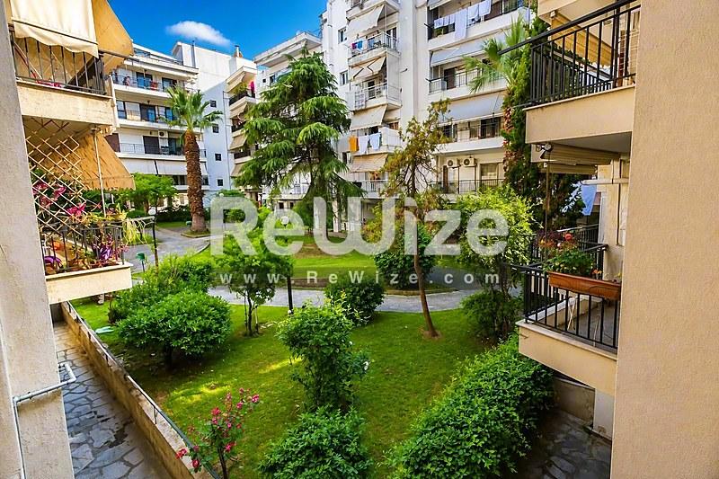 Πράσινη κοινόχρηστη αυλή διαμερίσματος στη Χαλκιδική με δέντρα και φυτεία.