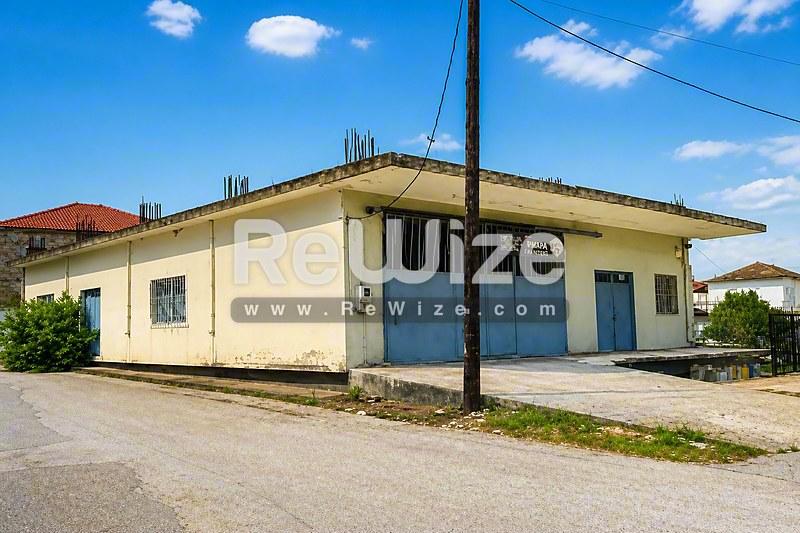 Βιομηχανικό κτίριο στη Χαλκιδική με κίτρινη πρόσοψη, μπλε πόρτες και λειτουργικό μονοώροφο σχέδιο.