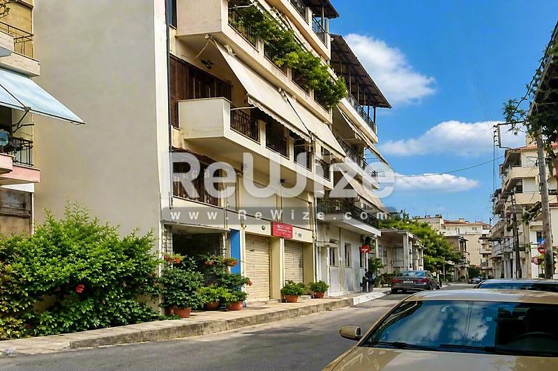 Πρόσοψη διαμερίσματος στην Χαλκιδική με μπαλκόνια και καταστήματα στο ισόγειο.