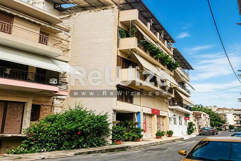 Πρόσοψη διαμερίσματος κατοικίας στη Χαλκιδική με πολλαπλά μπαλκόνια και καταστήματα ισογείου.