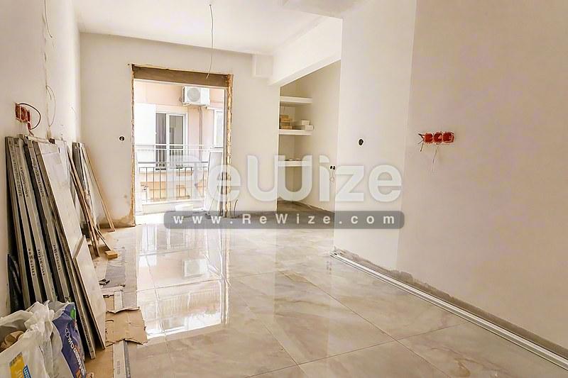 Φωτεινό και ευρύχωρο σαλόνι διαμερίσματος στη Χαλκιδική με γυαλιστερά μαρμάρινα πατώματα και πρόσβαση σε μπαλκόνι.