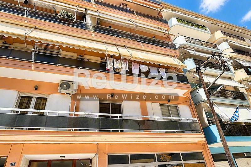 Πορτοκαλί και λευκή πρόσοψη σύγχρονου κτιρίου διαμερισμάτων στη Χαλκιδική με πολλά μπαλκόνια.