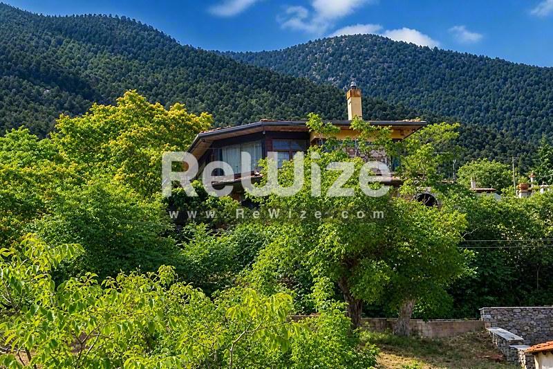 Σύγχρονη μεζονέτα περιτριγυρισμένη από πράσινη βλάστηση στη Χαλκιδική, με σύγχρονη αρχιτεκτονική και θέα στα βουνά.