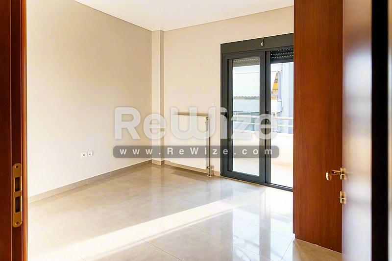 Φωτεινό σαλόνι α独立ής κατοικίας στη Χαλκιδική με μαρμάρινο δάπεδο και γαλλικές πόρτες που ανοίγουν σε βεράντα.