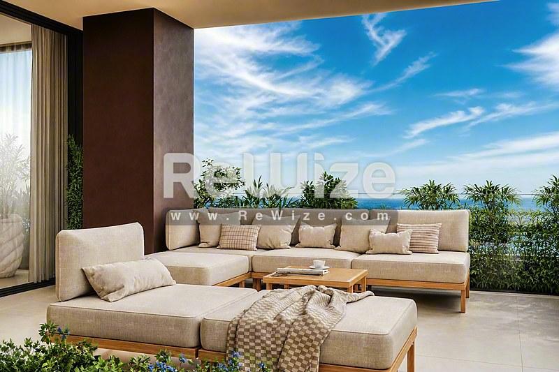 Πολυτελής βεράντα της βίλας rw-7456 στη Χαλκιδική με θέα στη θάλασσα, κρεμ σεζλόνγκ και μεσογειακό τοπίο.