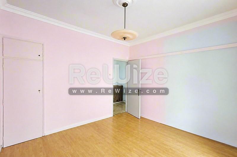 Φωτεινό υπνοδωμάτιο σε διαμέρισμα της Χαλκιδικής με ξύλινο δάπεδο και πολλαπλά παράθυρα.