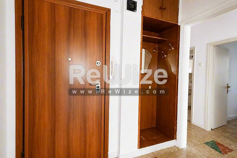 Είσοδος σύγχρονου διαμερίσματος στη Χαλκιδική με ξύλινη πόρτα, ψηφιακή κλειδαριά και ανοιχτή ντουλάπα.