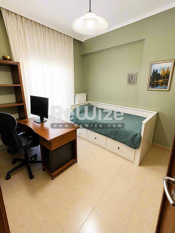 Συμπαγές υπνοδωμάτιο στο ακίνητο Χαλκιδικής rw-7479 με κρεβάτι αποθήκευσης, γραφείο και πράσινους τοίχους.
