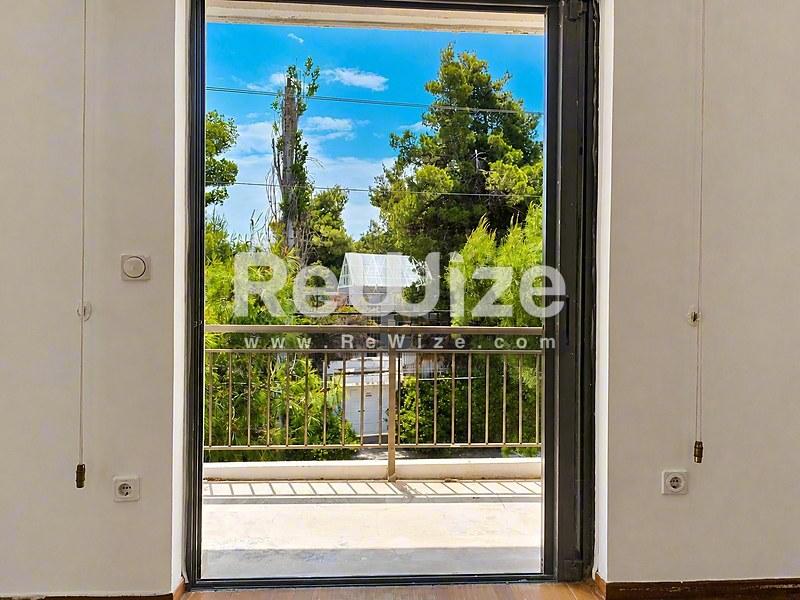 Μπαλκόνι της rw-7551 στη Χαλκιδική με θέα σε πράσινα δέντρα και γαλάζιο ουρανό.