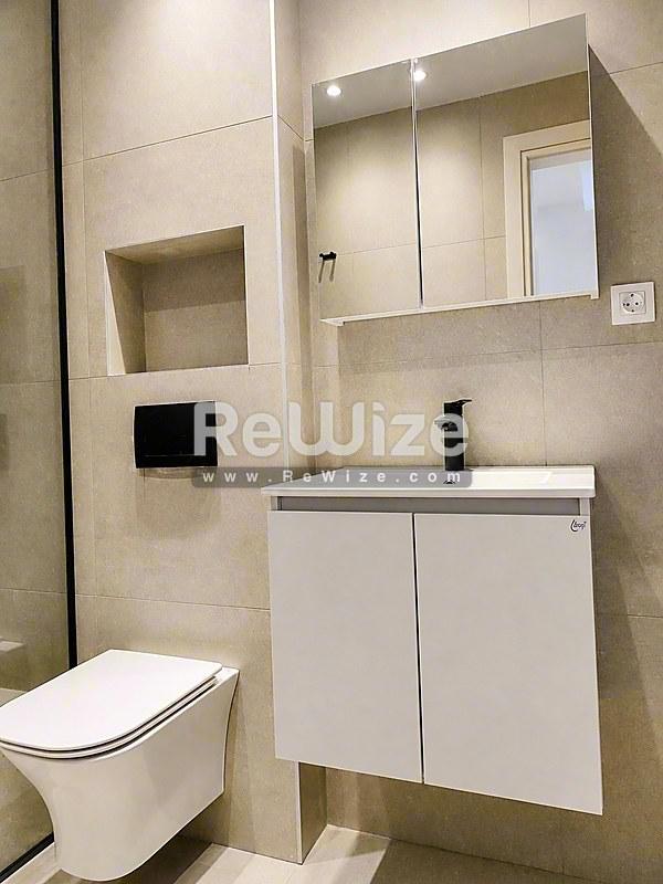 Σύγχρονο μπάνιο στην ιδιότητα Halkidiki rw-7556 με λευκή νιπτήρα, τοίχο τουαλέτας και ενσωματωμένη αποθήκευση.