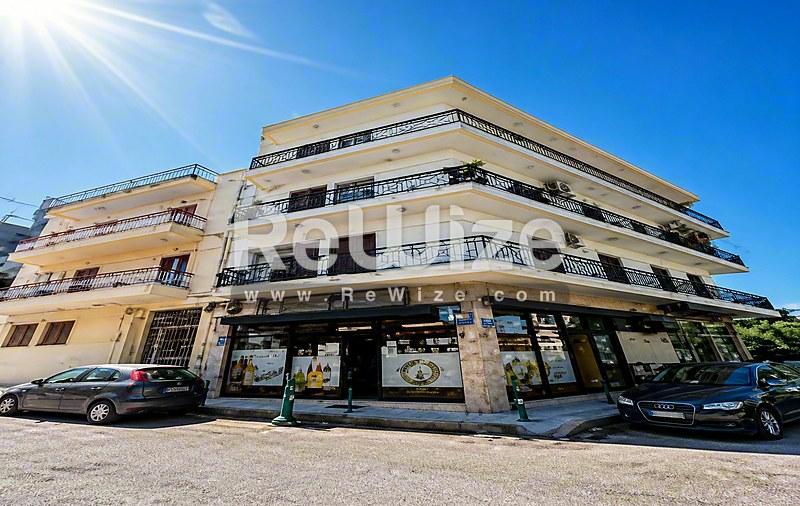 Πρόσοψη κτιρίου διαμερισμάτων στην παραλία της Χαλκιδικής με καταστήματα ισογείου και σύγχρονα μπαλκόνια.
