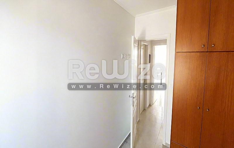 Φωτεινός διάδρομος στο ακίνητο Halkidiki rw-7618 με λευκούς τοίχους και ξύλινη ντουλάπα.