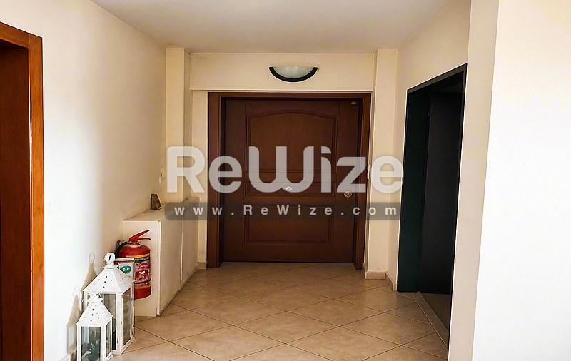 Ευρύχωρος διάδρομος εισόδου του ακινήτου rw-7618 στη Χαλκιδική με ξύλινη πόρτα και πλακόστρωτο δάπεδο.