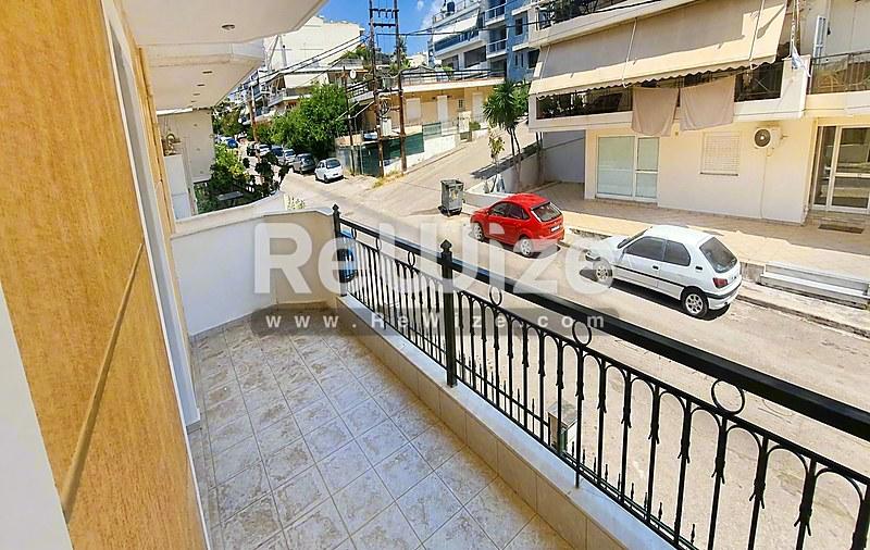 Ευρύχωρη βεράντα διαμερίσματος στη Χαλκιδική με θέα στο δρόμο και χώρο στάθμευσης παρακάτω.