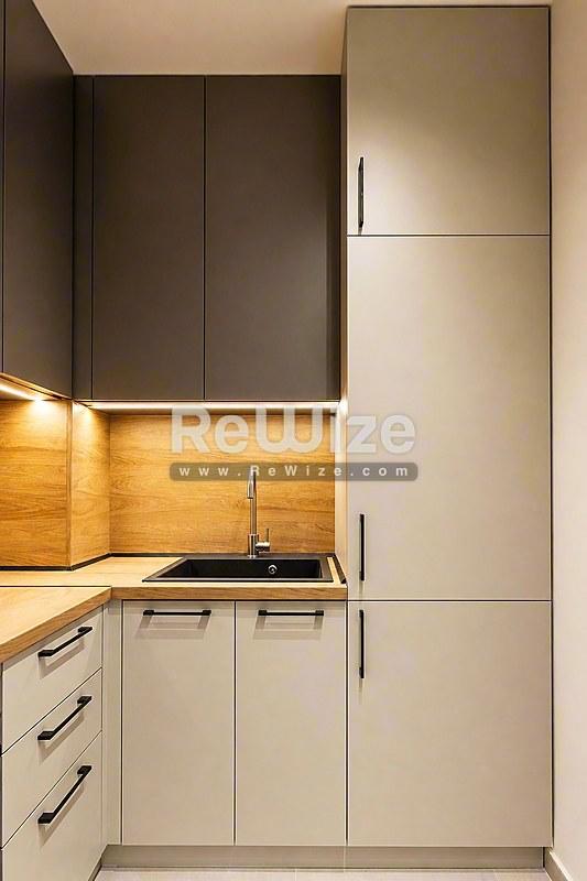 Σύγχρονη συμπαγής κουζίνα με ζεστό ξύλινο backsplash και μινιμαλιστικά έπιπλα σε διαμέρισμα της Χαλκιδικής.