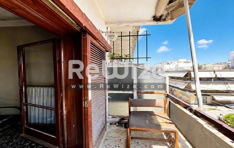 Ευρύχωρο μπαλκόνι του ακινήτου rw-7622 στη Χαλκιδική με καθαρή θέα της πόλης και χώρο καθίσματος.