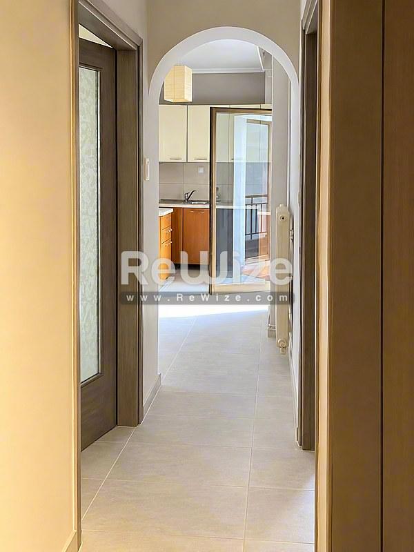 Φωτεινός διάδρομος του ακινήτου rw-7625 στη Χαλκιδική με σύγχρονο δάπεδο και καμπυλωτή πόρτα.