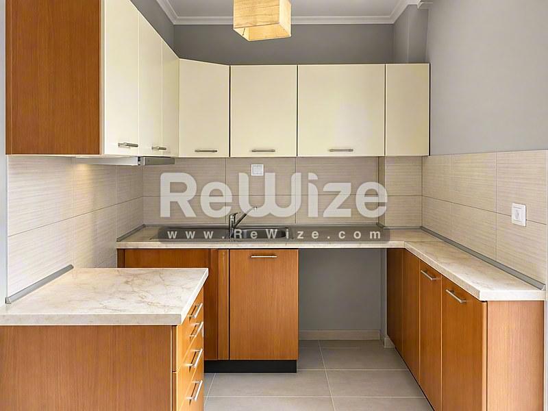 Σύγχρονη κουζίνα στο διαμέρισμα Halkidiki rw-7625 με ξύλινα έπιπλα και μαρμάρινο πάγκο.