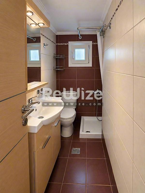 Σύγχρονο μπάνιο στο διαμέρισμα Halkidiki rw-7626 με νιπτήρα, τουαλέτα και ντουζ.