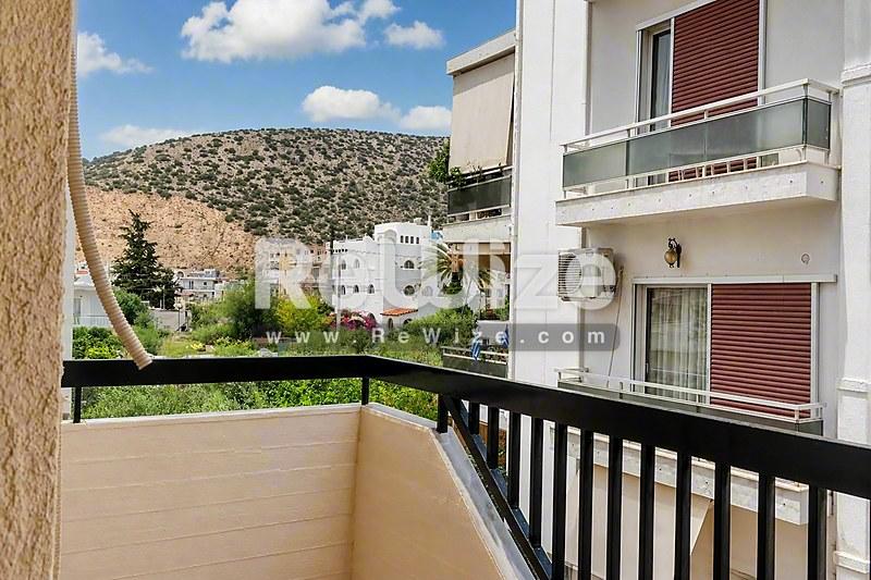 Μπαλκόνι διαμερίσματος στη Χαλκιδική με θέα σε πράσινους κήπους και γύρω λόφους.