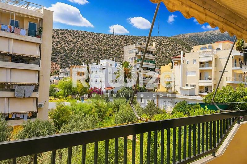 Μπαλκόνι διαμερίσματος στη Χαλκιδική με θέα σε κτήρια μεσογειακού στιλ και πράσινους λόφους.