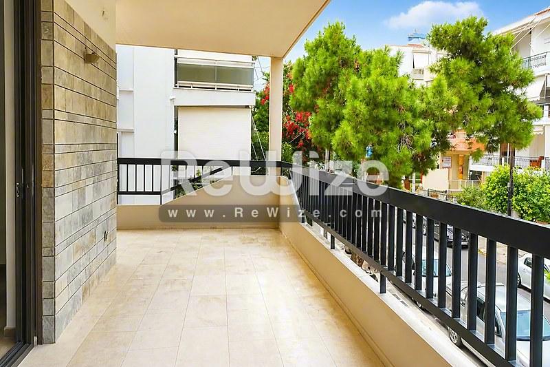 Ευρύχωρη βεράντα διαμερίσματος στη Χαλκιδική με μαύρες κιγκλιδώματα και θέα σε πράσινη φύση.