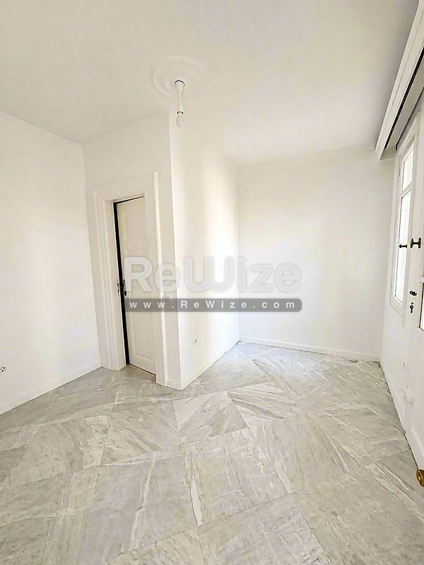 Άδειο υπνοδωμάτιο με ανοιχτόχρωμα πλακάκια και λευκούς τοίχους στη Χαλκιδική.