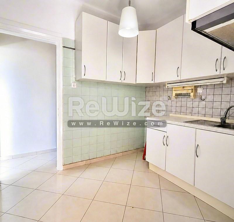 Φωτεινή κουζίνα του rw-7712 στη Χαλκιδική με λευκά ντουλάπια, μέντα πλακάκια και ευρύχωρο μπεζ δάπεδο.