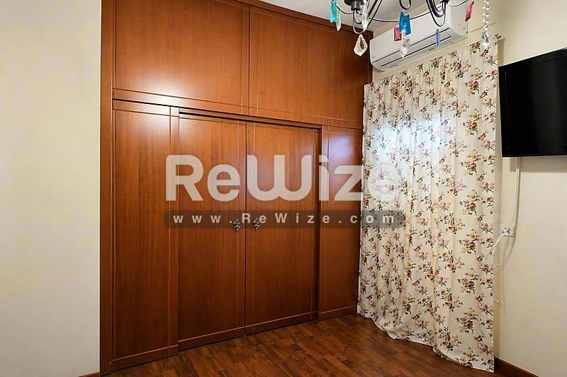 Просторна спаваћа соба у самостојећој кући у Халкидики, са дрвеним ормарима и паркетом.