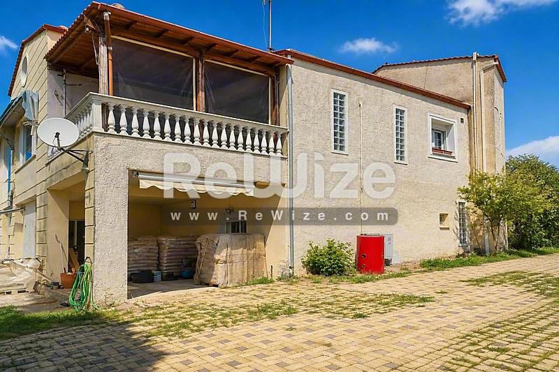 Πρόσοψη μονοκατοικίας στη Χαλκιδική με γκαράζ ισογείου, μπαλκόνι ορόφου και επένδυση πέτρας.