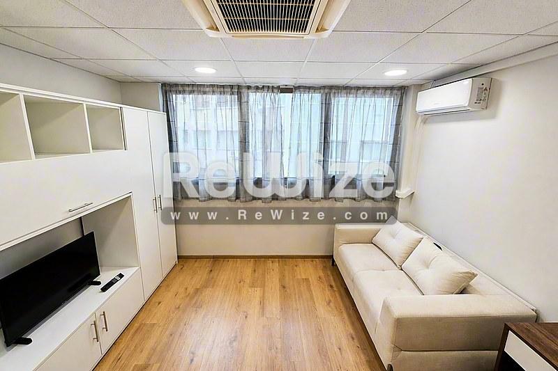 Φωτεινό σαλόνι διαμερίσματος στη Χαλκιδική με ξύλινα δάπεδα, σύγχρονα έπιπλα και μεγάλα παράθυρα.