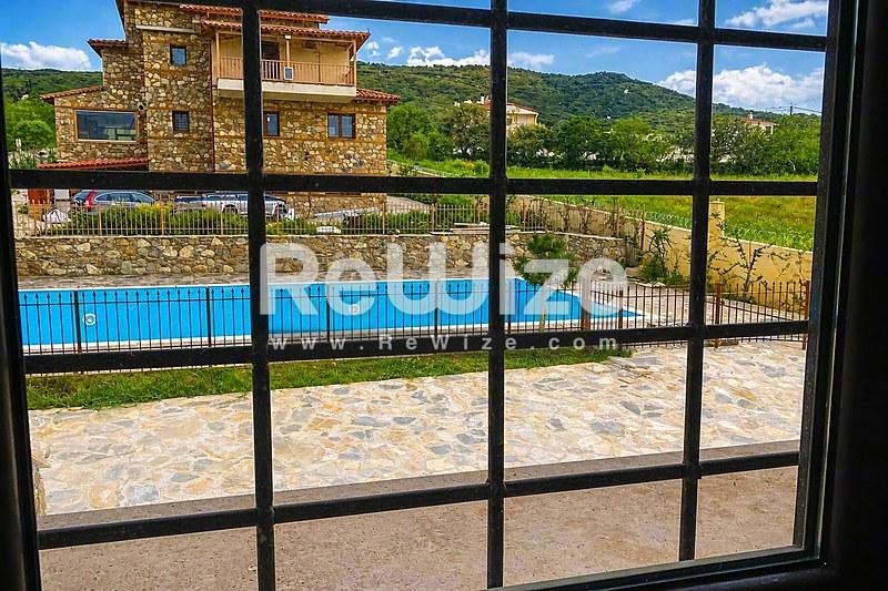 Κρυστάλλινη πισίνα διαμερίσματος στη Χαλκιδική με θέα στα πράσινα βουνά και τη φύση.