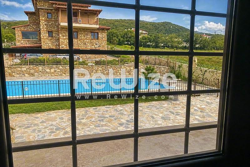 Κρυστάλλινη πισίνα της διαμέρισμα στη Χαλκιδική με πέτρινη βεράντα και θέα στα βουνά.