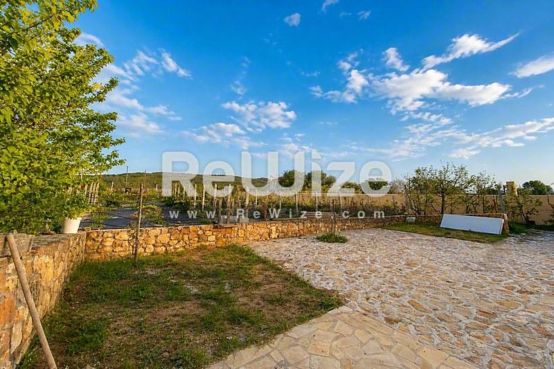 Просторна αυλή διαμερίσματος στη Χαλκιδική με πλακόστρωτη βεράντα και κήπο.