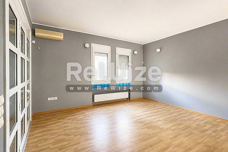 Φωτεινό σαλόνι με ξύλινα δάπεδα και γκρίζα τοίχους σε μονοκατοικία στη Χαλκιδική.