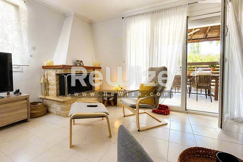 Φωτεινό σαλόνι μεζονέτας στη Χαλκιδική με τζάκι, σύγχρονα έπιπλα και πρόσβαση στον κήπο.