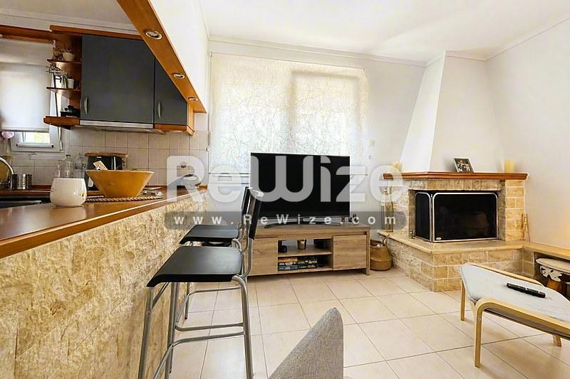 Φωτεινό σαλόνι μεζονέτας στη Χαλκιδική με τζάκι, τηλεόραση και σύγχρονη κουζίνα.