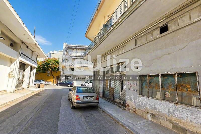 Πρόσοψη οικοπέδου στη Χαλκιδική με παραδοσιακά μεσογειακά κτίρια, λευκές τοίχους και καταστήματα ισογείου.