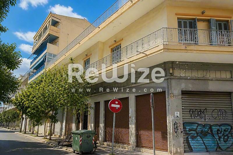 Πρόσοψη μεζονέτας στη Χαλκιδική με πολυώροφο κίτρινο κτίριο, καταστήματα ισογείου και κατοικίες ανωτέρων ορόφων.