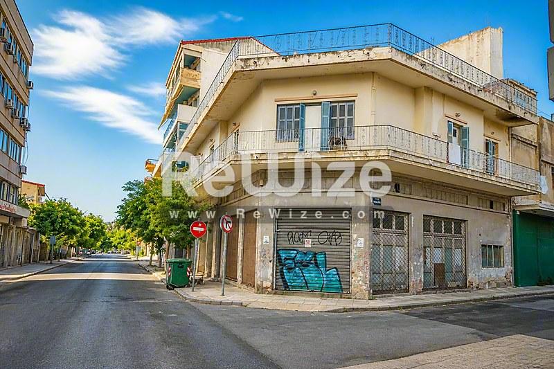 Γωνιακή όψη οικοπέδου μεζονέτας στη Χαλκιδική με καμπύλα μπαλκόνια και χώρο εμπορικής χρήσης.