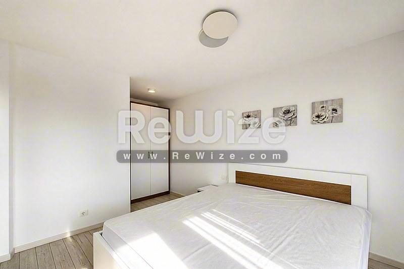 Φωτεινό master bedroom διαμερίσματος στη Χαλκιδική με κρεβάτι, ξύλινη διακόσμηση και ενσωματωμένη ντουλάπα.