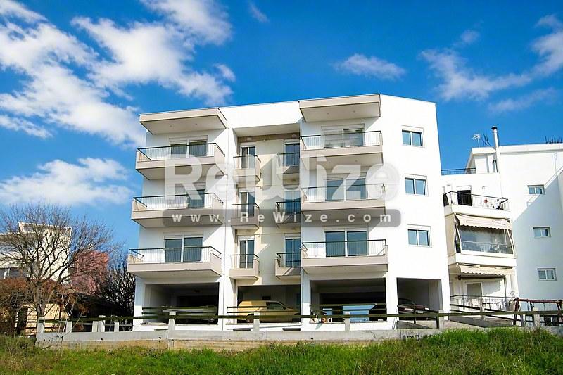 Σύγχρονη πολυκατοικία στη Χαλκιδική με λευκή όψη, μπαλκόνια και χώρο στάθμευσης.