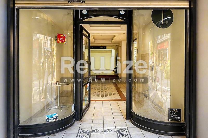 Σύγχρονη είσοδος καταστήματος με καμπύλες γυάλινες πόρτες στη Χαλκιδική, με κομψό μαύρο πλαίσιο.