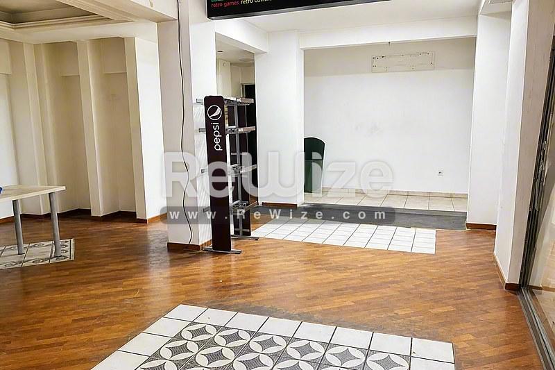 Ευρύχωρος διάδρομος καταστήματος στη Χαλκιδική με ξύλινο δάπεδο, λευκές κολώνες και φυσικό φως.